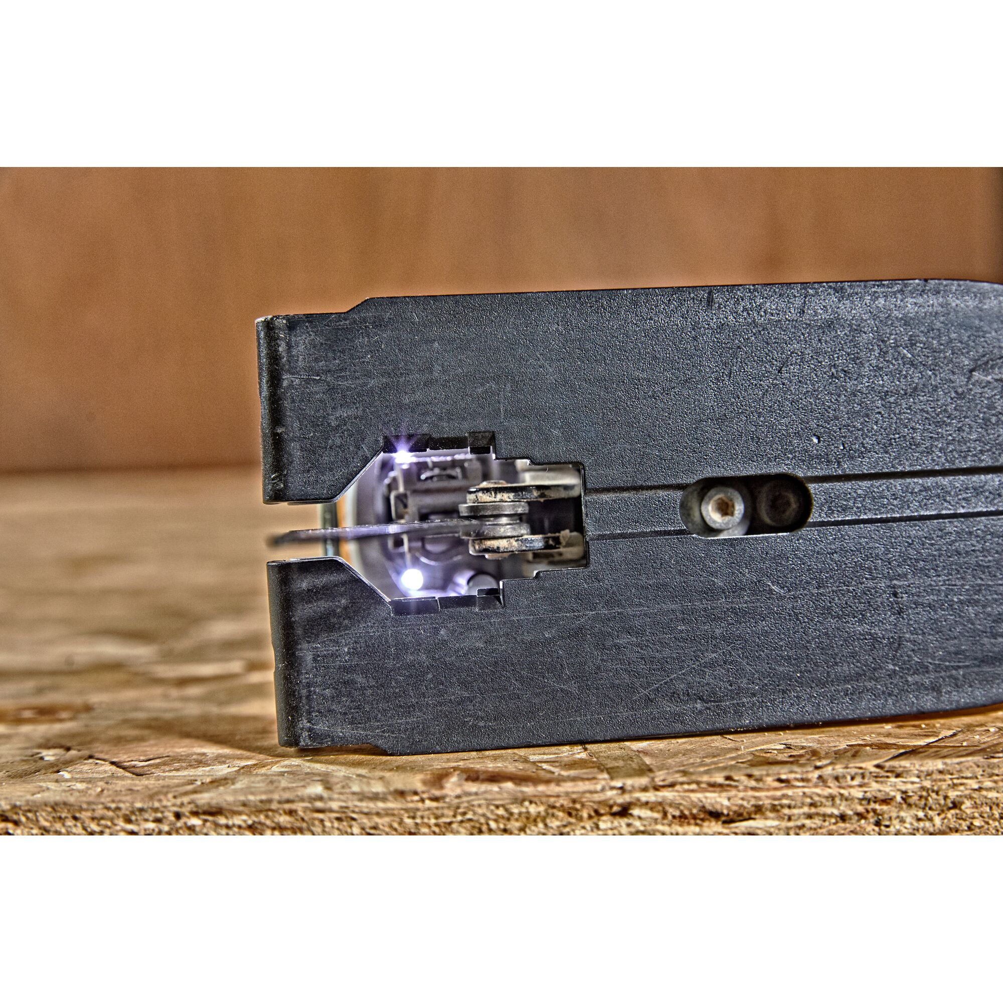 Close-up view of the front of a DEWALT jigsaw, showing the blade with LED work lights illuminated for better visibility on a wooden surface.