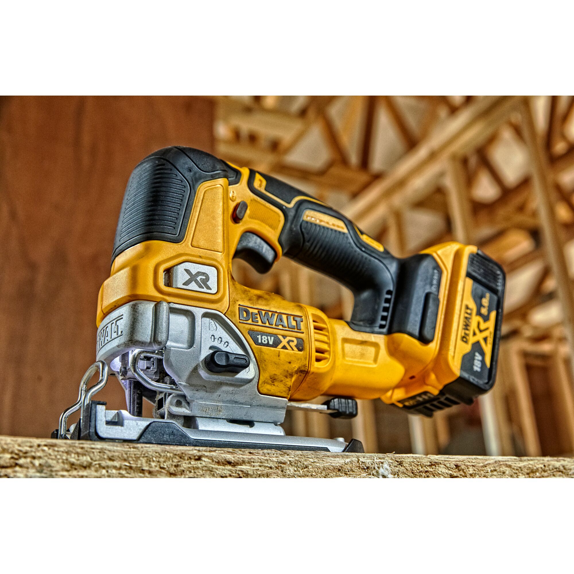 A close-up view of a DEWALT cordless 18V XR jigsaw tool resting on a piece of wood, set in a construction environment.