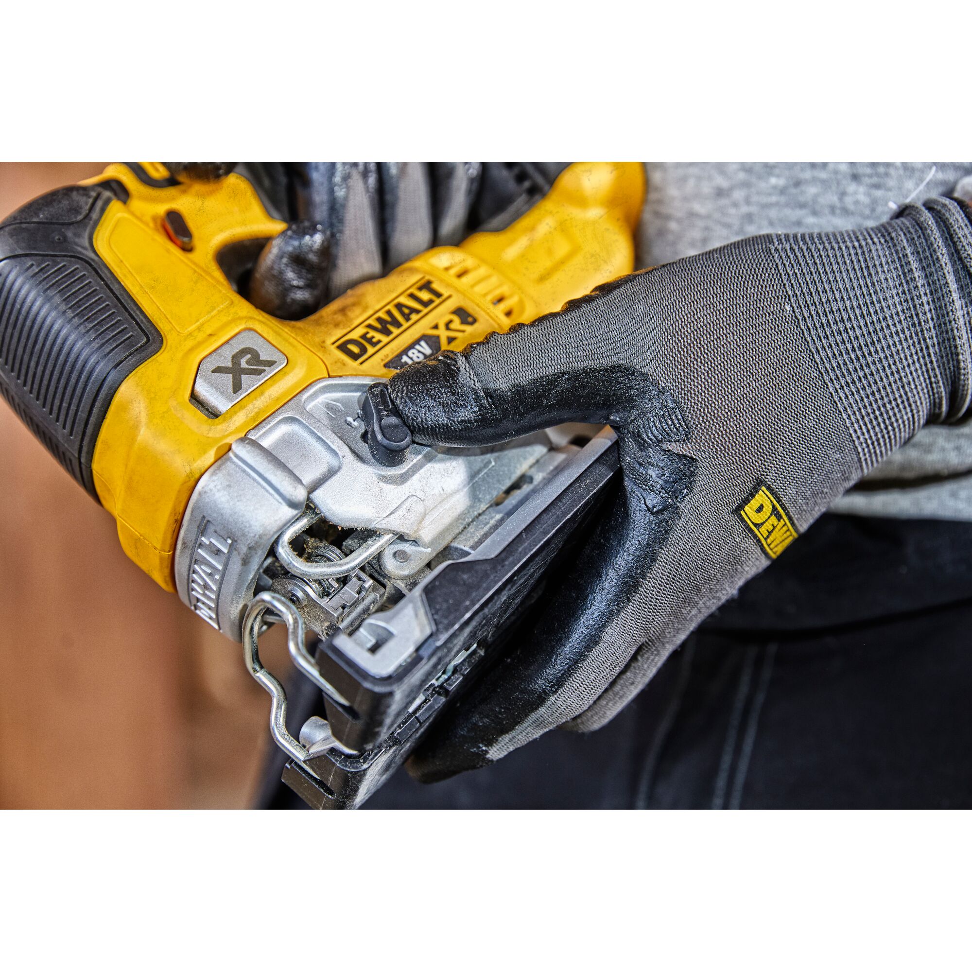 Close-up of a gloved hand holding a yellow DEWALT XR 18V jigsaw tool.